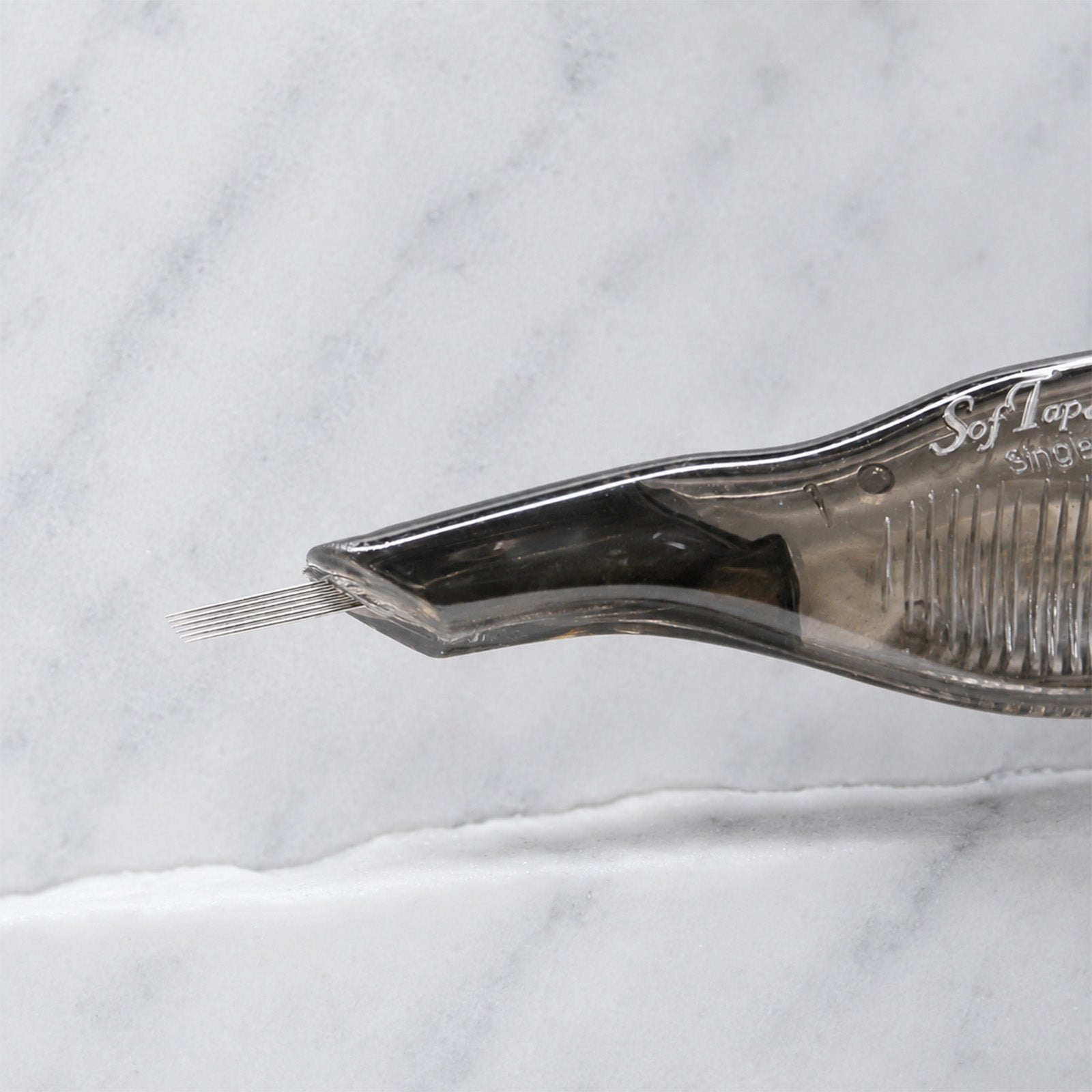 A close-up of SofTap 6 reg curve pmu needle disposable pen, resting on a white marble surface.