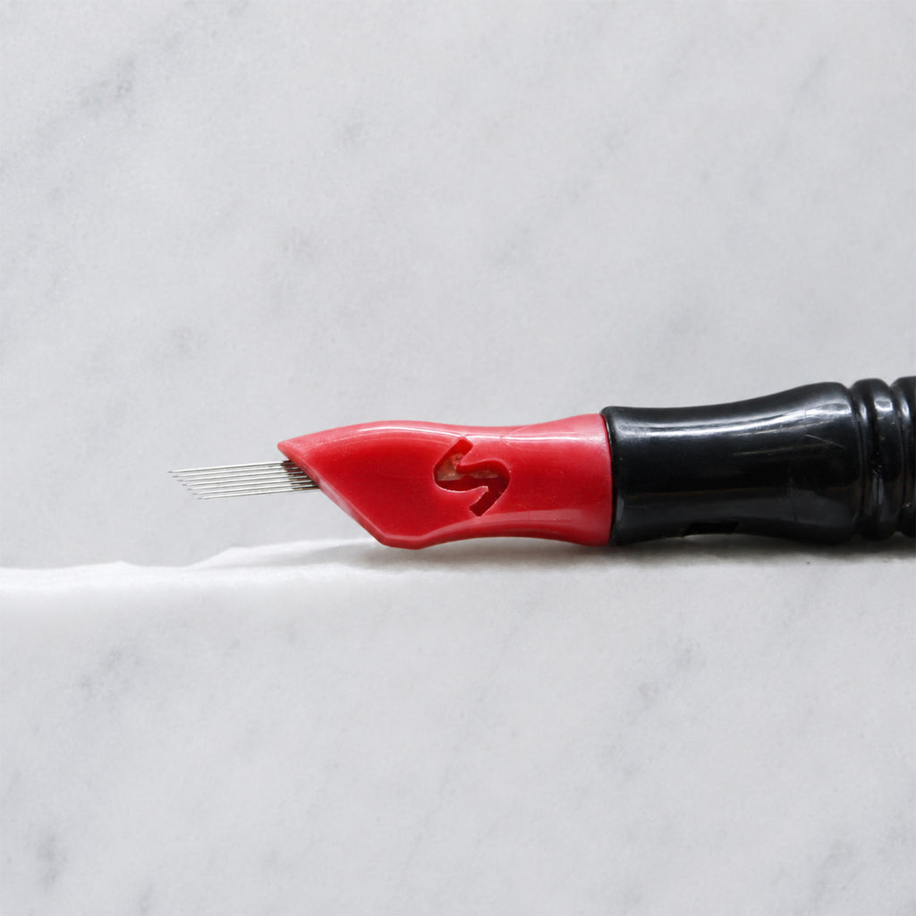A close-up of SofTap 7 pmu needle click tip, resting on a white marble surface.