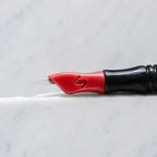 A close-up of SofTap 7 pmu needle click tip, resting on a white marble surface.