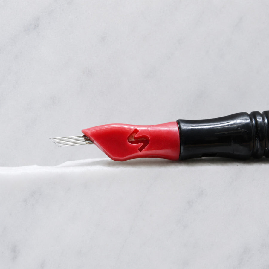A close-up of SofTap 7 pmu needle click tip, resting on a white marble surface.
