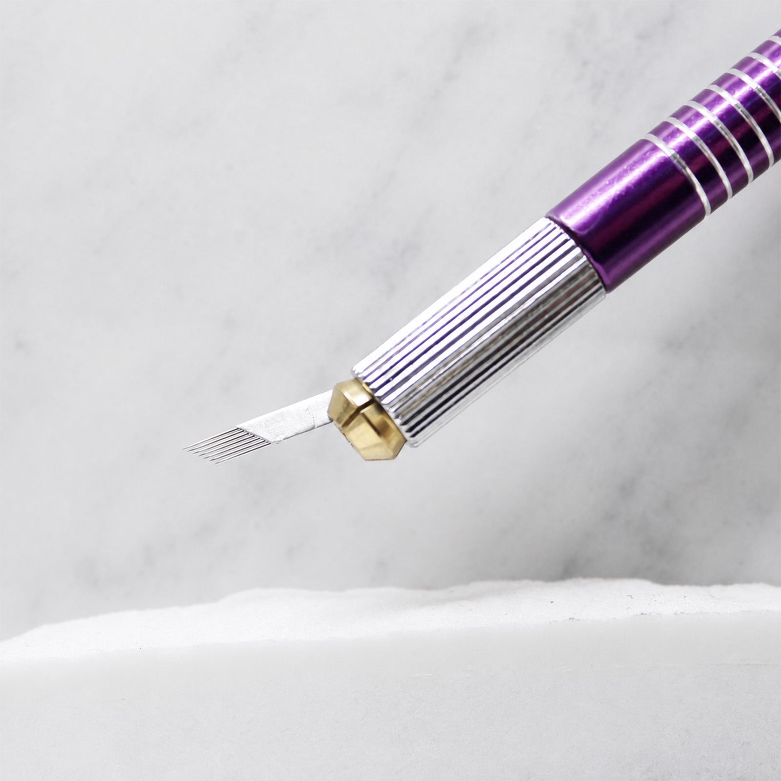 A close-up of SofTap 7 pmu needle foil cartridge, resting on a white marble surface.