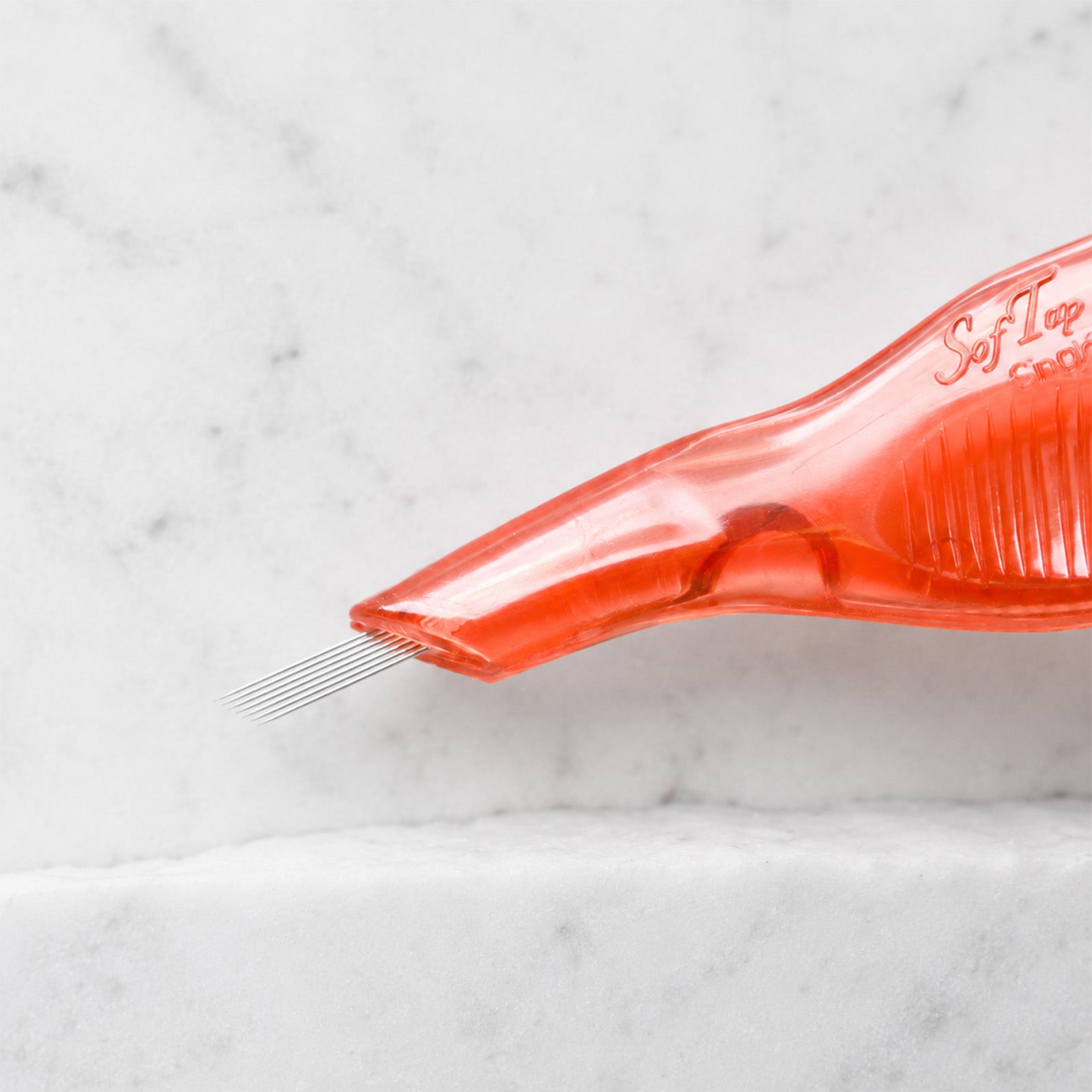 A close-up of SofTap 7 pmu needle disposable pen, resting on a white marble surface.