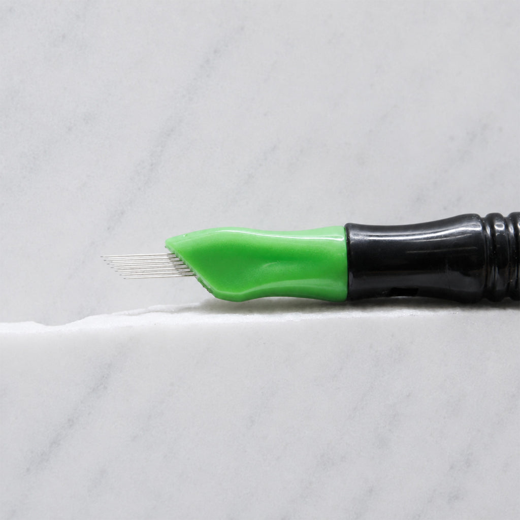 A close-up of SofTap 7 smudger pmu needle click tip, resting on a white marble surface.