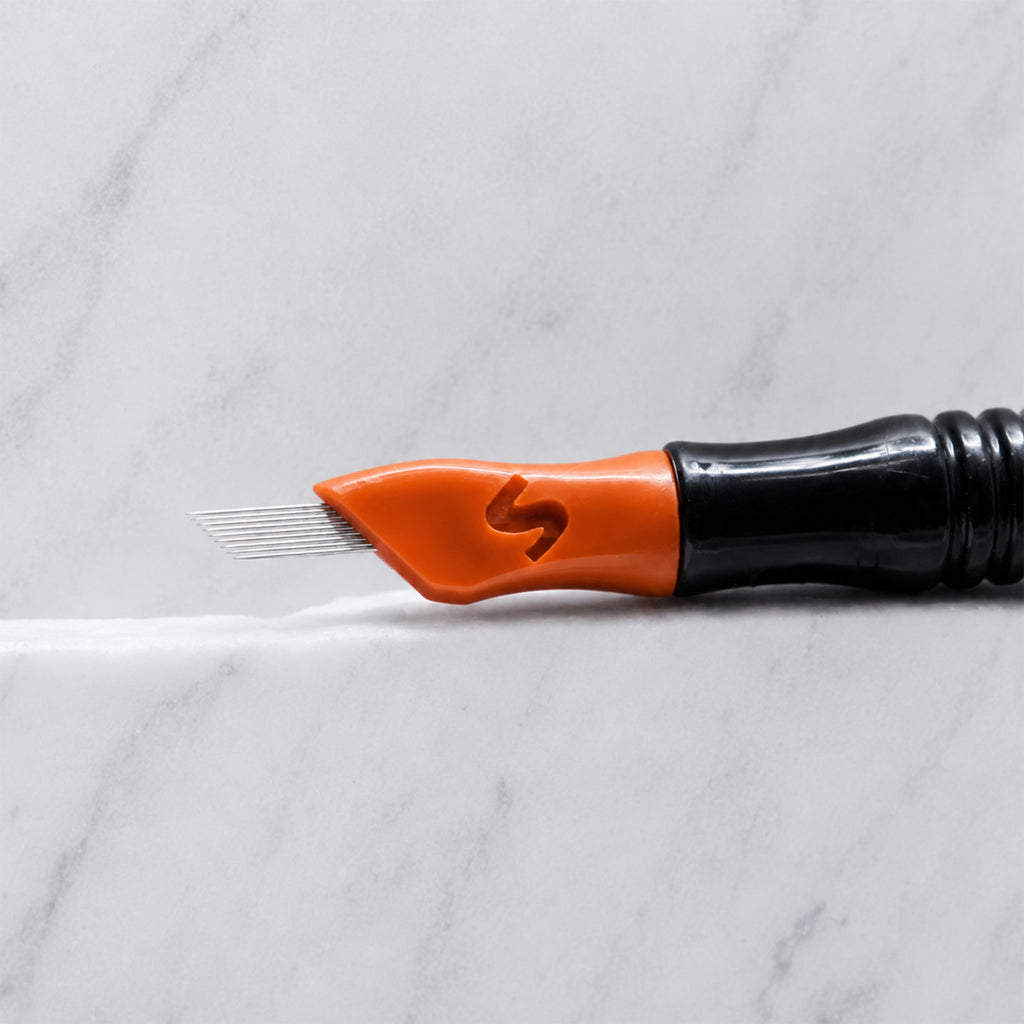 A close-up of SofTap 70 pmu needle click tip, resting on a white marble surface.