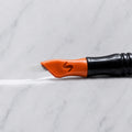 A close-up of SofTap 70 pmu needle click tip, resting on a white marble surface.