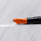 A close-up of SofTap 70 pmu needle click tip, resting on a white marble surface.