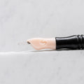 A close-up of SofTap 84 pmu needle click tip, resting on a white marble surface.
