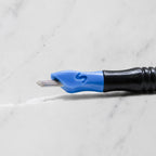 A close-up of SofTap 87 round pmu needle click tip, resting on a white marble surface.