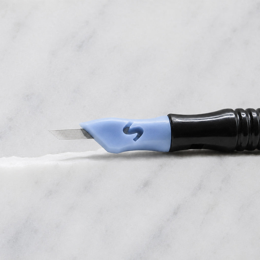 A close-up of SofTap 9 pmu needle click tip, resting on a white marble surface.