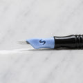 A close-up of SofTap 9 pmu needle click tip, resting on a white marble surface.