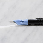 A close-up of SofTap 9 pmu needle click tip, resting on a white marble surface.