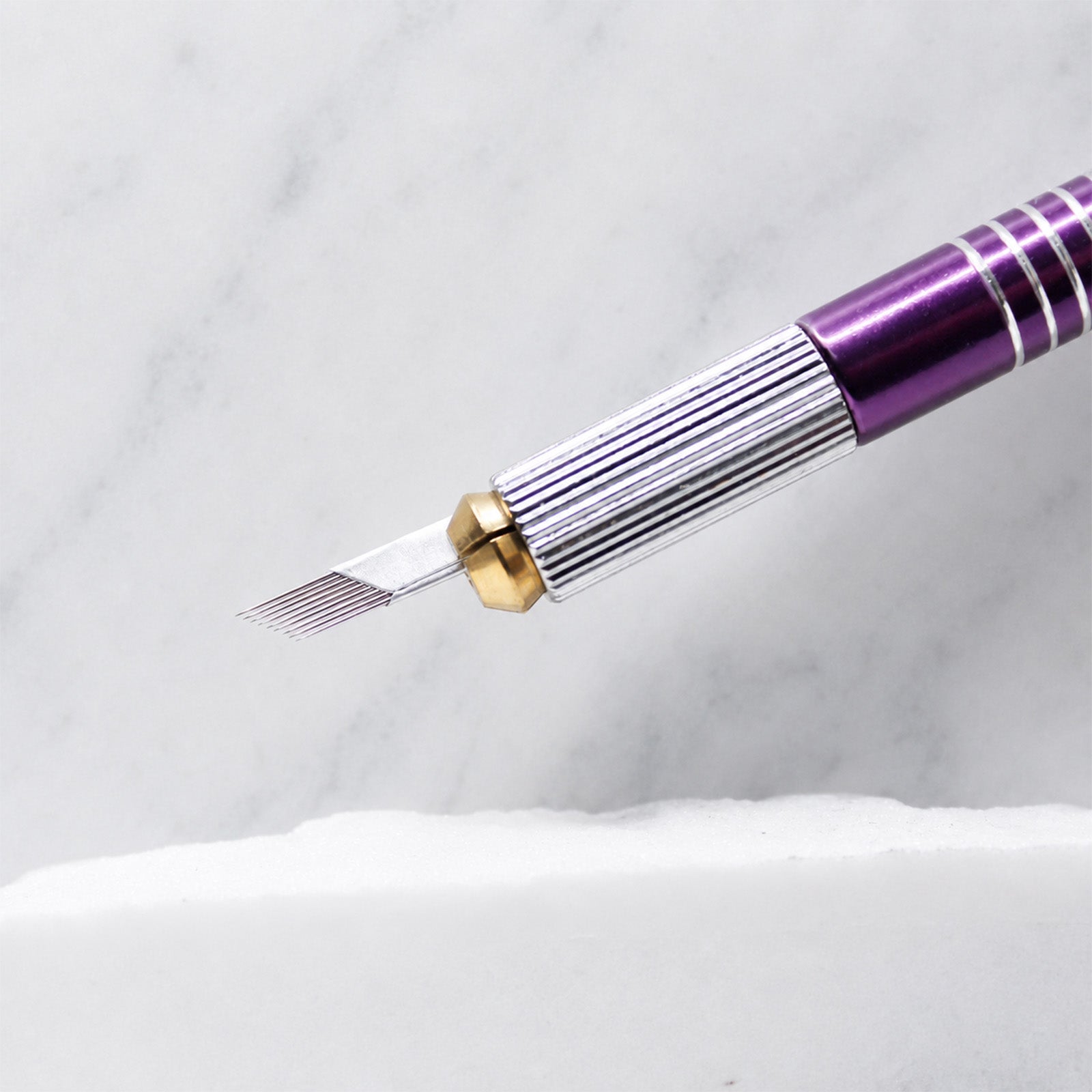 A close-up of SofTap 9 pmu needle foil cartridge, resting on a white marble surface.