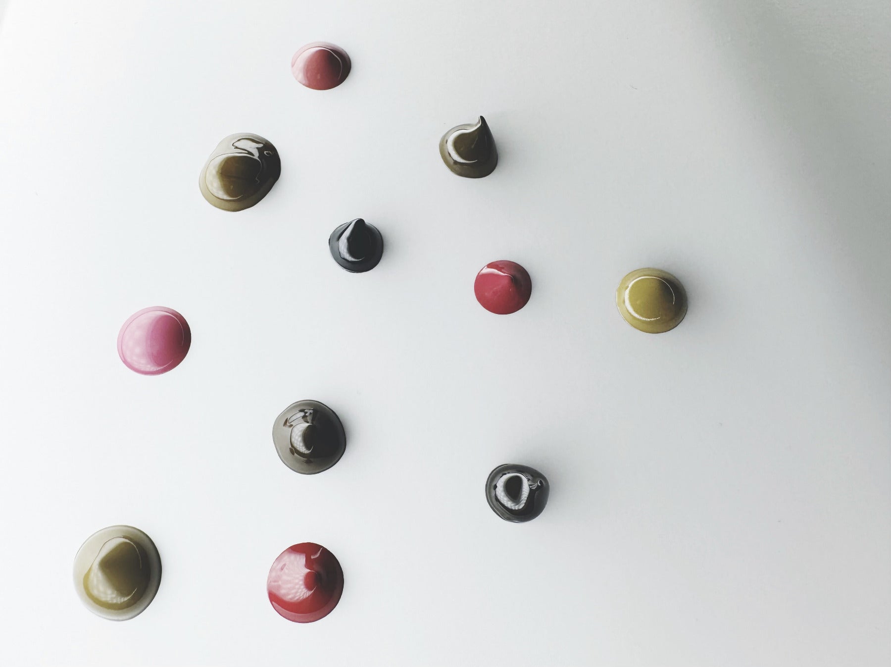 pigment droplets pink red black brown and blonde colors on white background